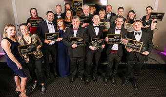 2025 Business Awards winners with their trophies and certificates