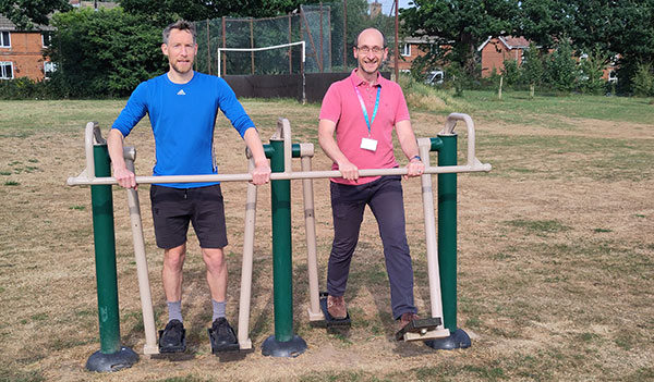 Two people on outdoor gym equipment in the park
