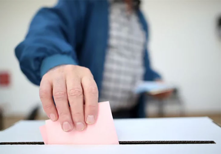 Person putting ballot paper into a ballot box