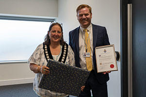 Two people holding certificates, smiling at the camera