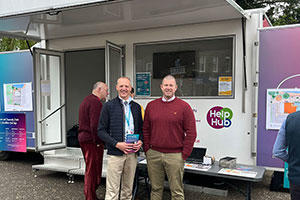 Two men, standing in from of information van, smiling.