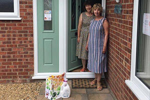 Chris and Shelagh Cottrell on a doorstep with a bag of supplies in front of them