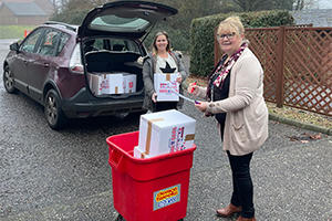 Two ladies putting boxes of toys into the boot of a car