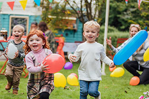 Young children running outside with balloons
