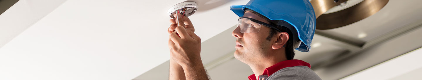 hanydperson changing a smoke detector batteries