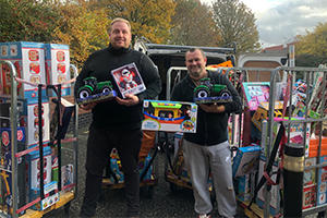 Jeremy Payne and Michael Downs holding children's toys and with two crates of christmas presents beside them