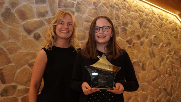 Young girl, smiling holding star trophy with blonde lady