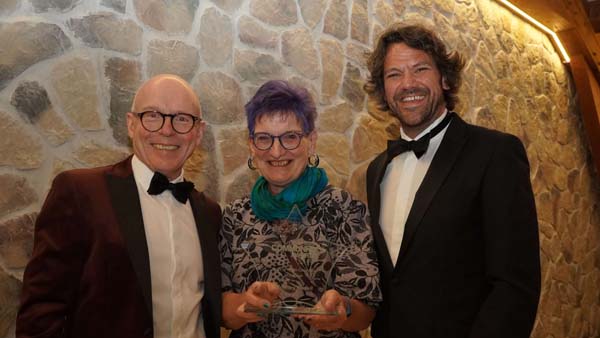 Lady receiving glass star trophy from two men in tuxedos