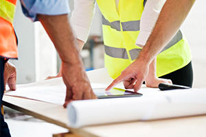 Three men looking at building plans on a table