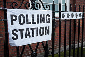 Polling station with a sign saying polling station and arrows pointing to the right directing people in