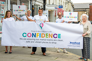 Leader of Broadland Council Shaun Vincent holding up a shop with confidence in Broadland banner with chaiman of the council karen vincent and other councillors