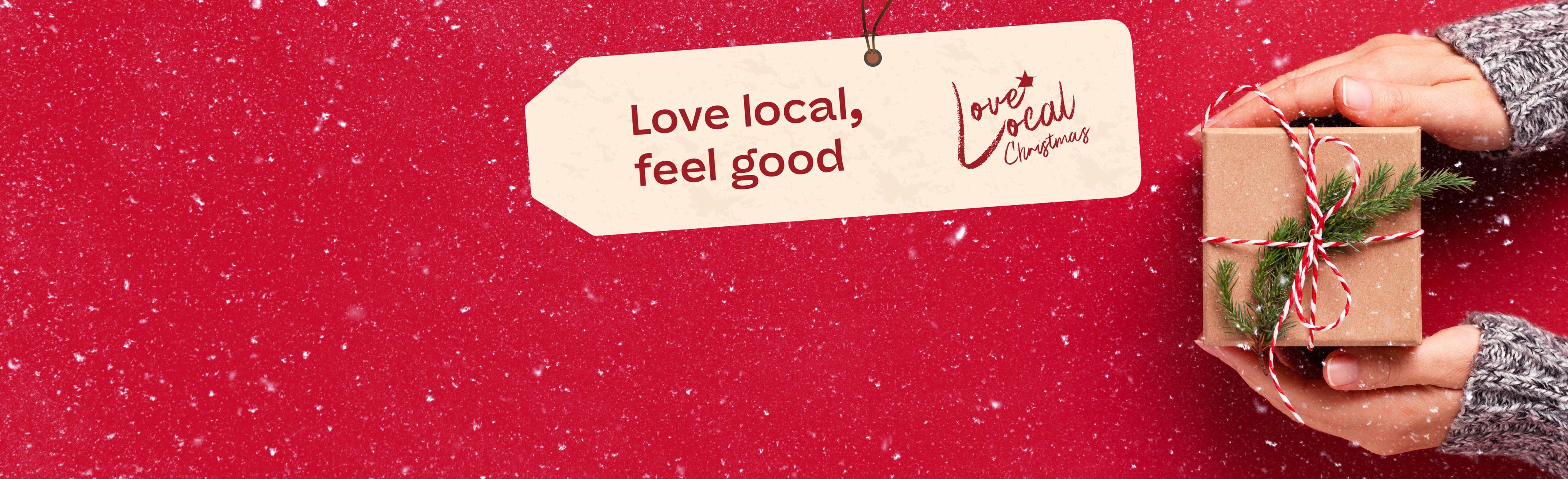 Love local, feel good. Love Local Christmas logo. Someone holding a present.