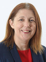 Lady with shoulder length brown hair, red top and blue jacket.