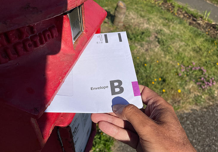 Voter putting their postal vote in a post box.