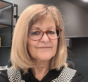 headshot of lady with blonde hair, wearing glasses and smiling at the camera