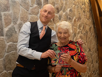 Man and lady standing on a stage. Lady holding an award. Both smiling at the camera.