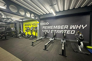 Exercise equipment in a gym, with motivational quotes written on the wall in the background