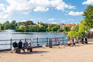 People sat on benches overlooking the water at Diss Mere