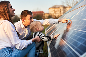 A young man and a woman looking at solar panels and touching them with their young son