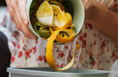 orange peel being tipped into a food waste bin