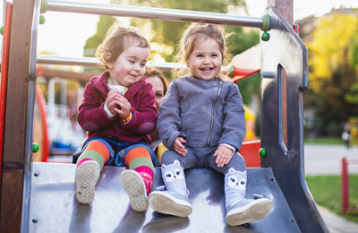 two young girls on a slide at a playground
