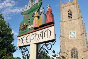 Reepham sign with a church tower behind it