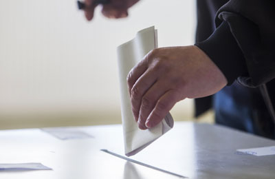 Someone putting a ballot paper into a ballot box