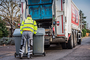 Bin man putting grey bins into a Veolia bin lorry