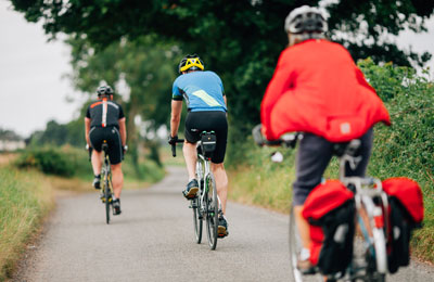 three cyclists going down a country lane