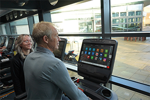 Man trying out the new equipment in the gym at Wymondham Leisure Centre with a member of staff assisting him